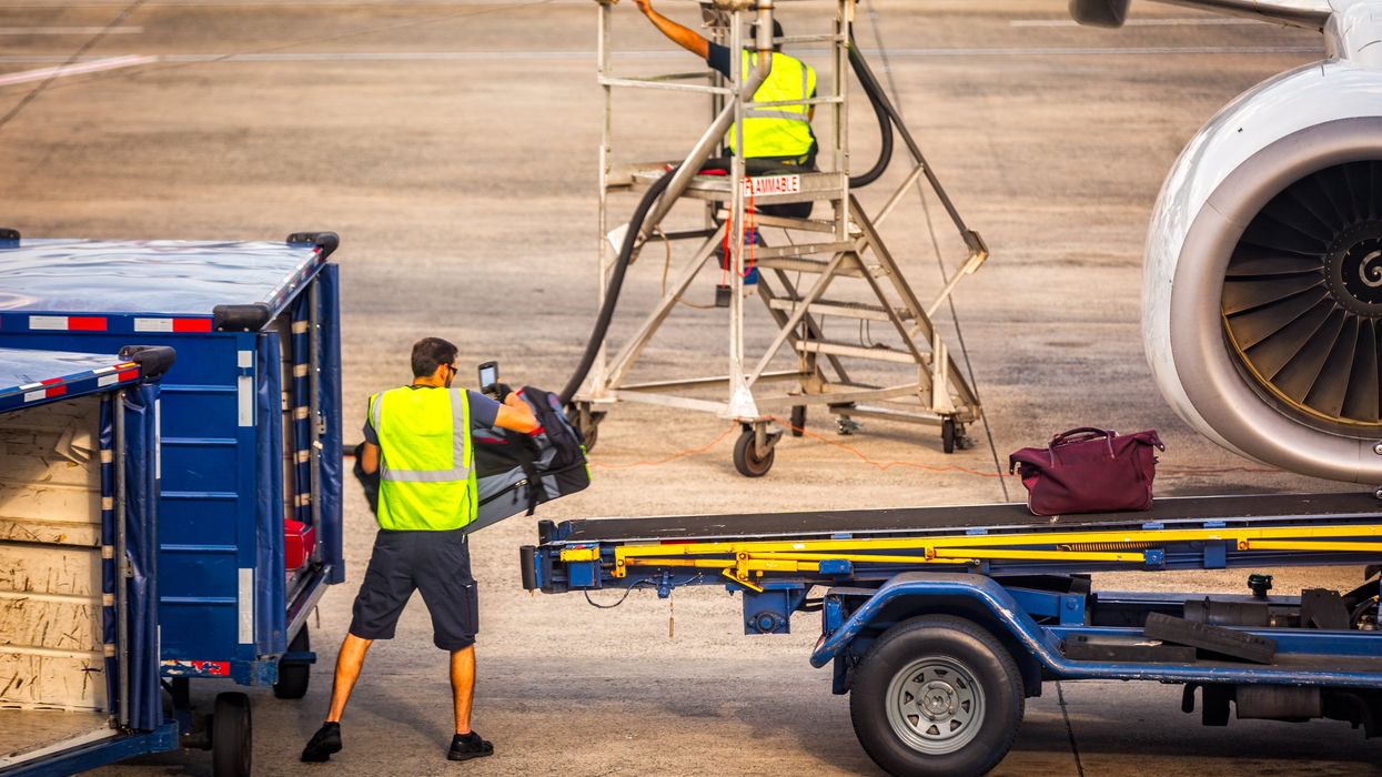 Airport worker loads baggage into an airplane (illustrative).