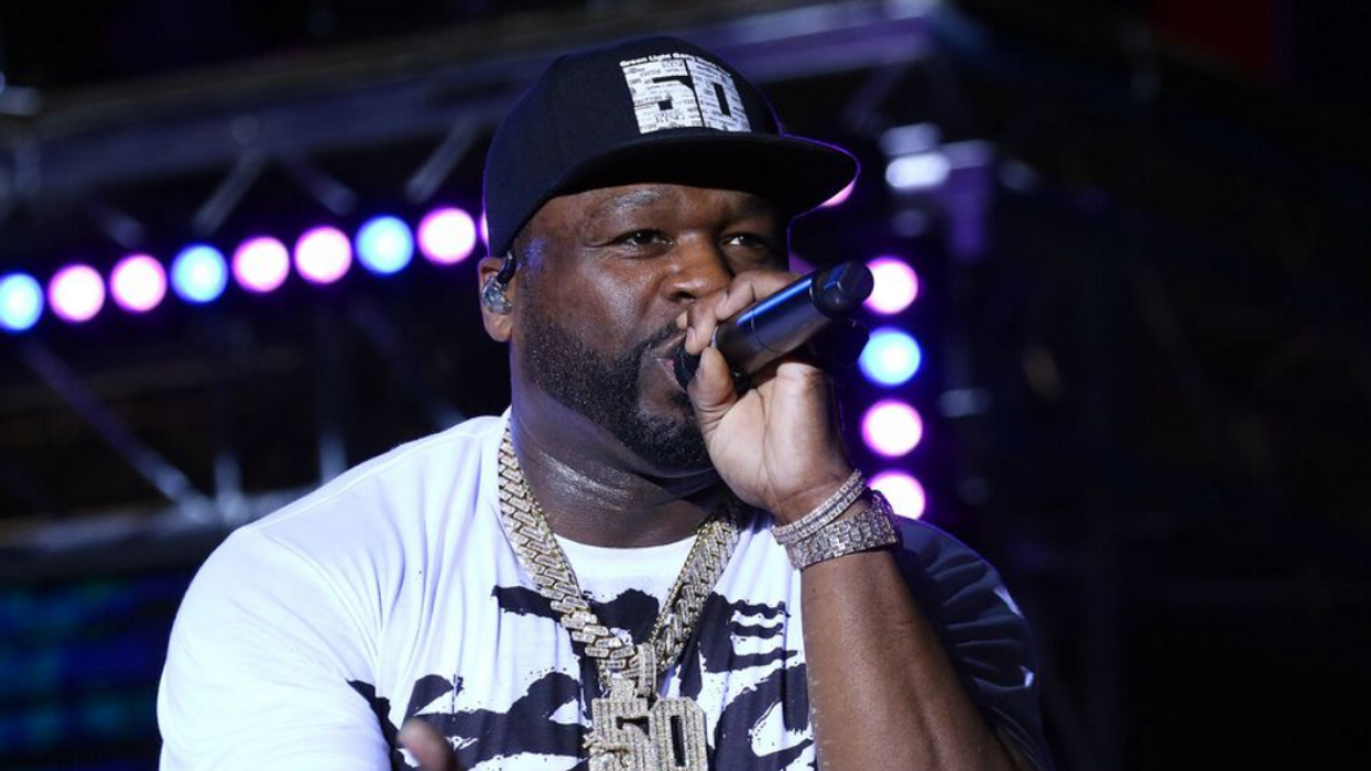 American rapper 50 Cent holds a microphone close to his mouth.