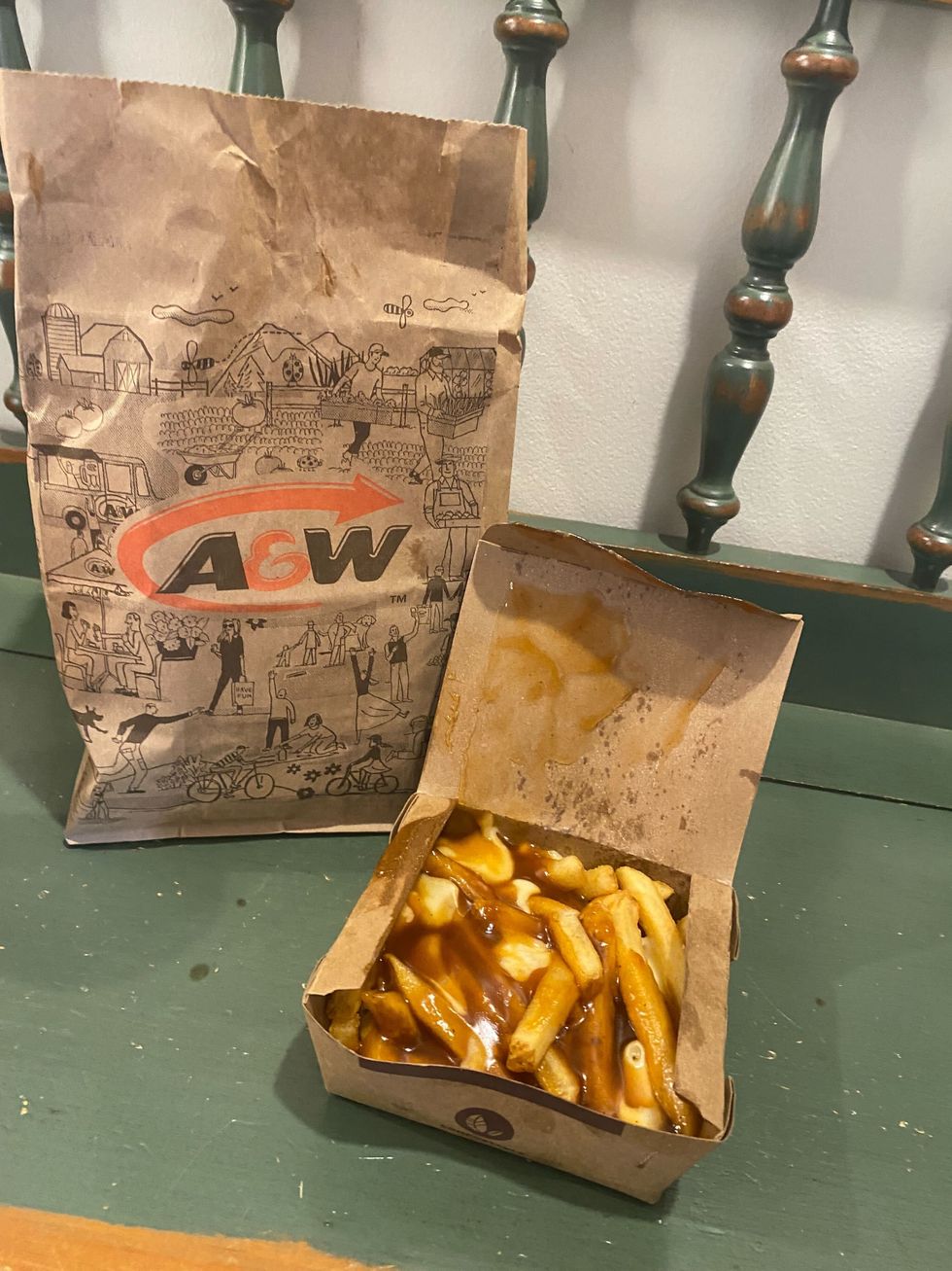 An A&W poutine on a green bench.