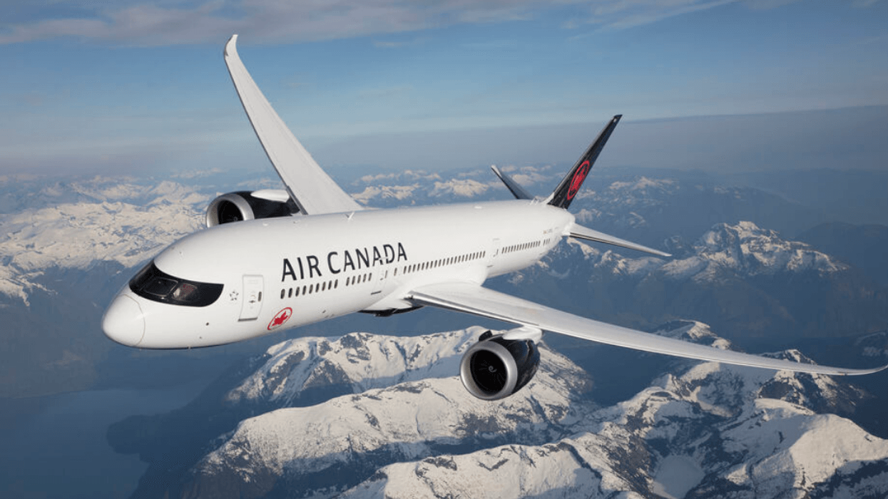 An Air Canada Boeing 787 Dreamliner flies over snowy mountain peaks.