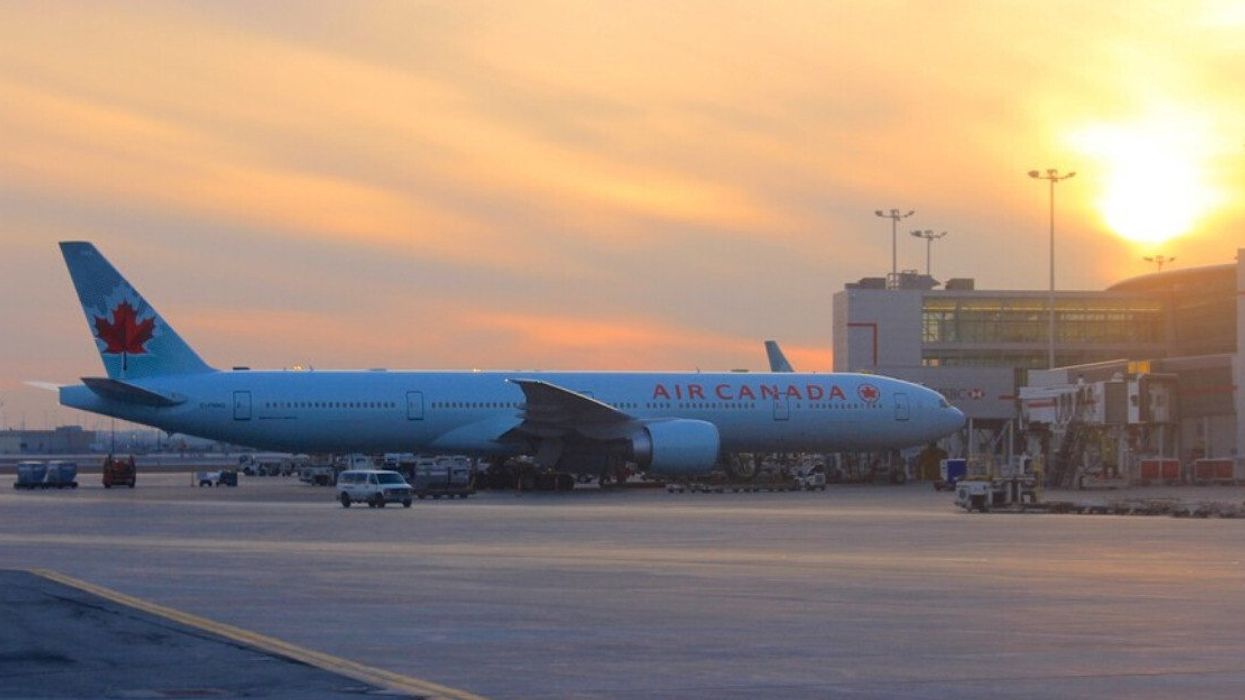 An Air Canada flight at an airport gate at sundown.