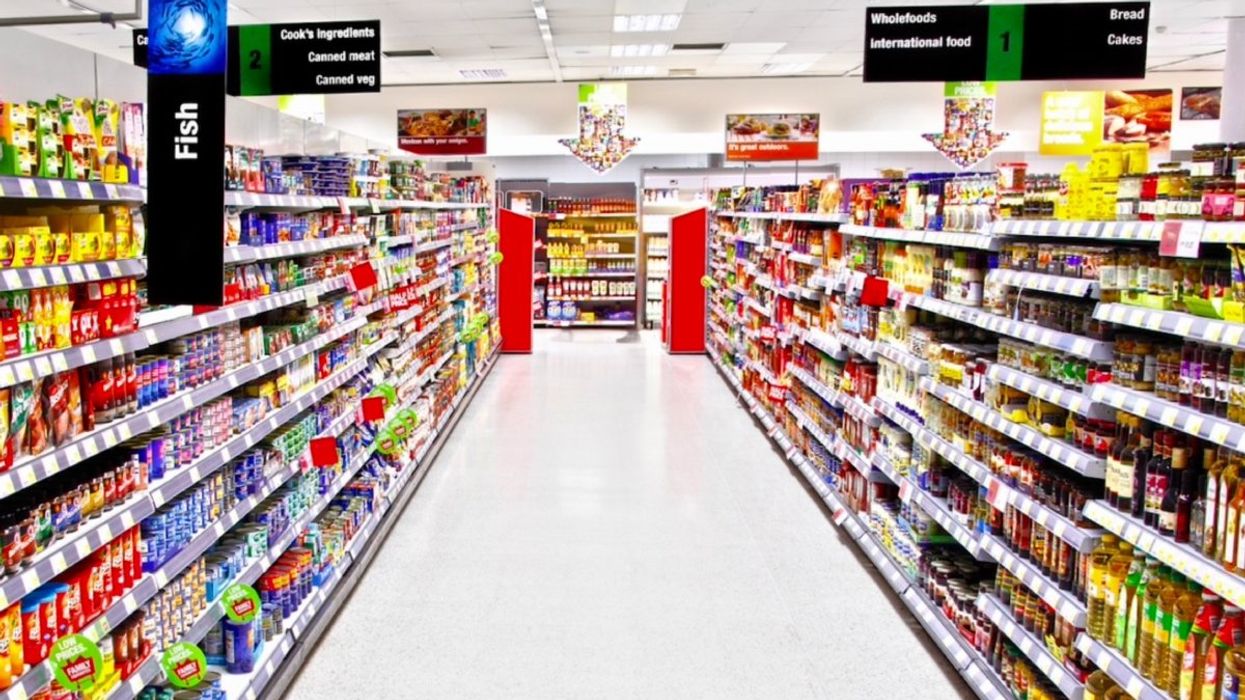 An empty grocery store aisle with dried foods, canned foods and sauces stacked atop shelves.