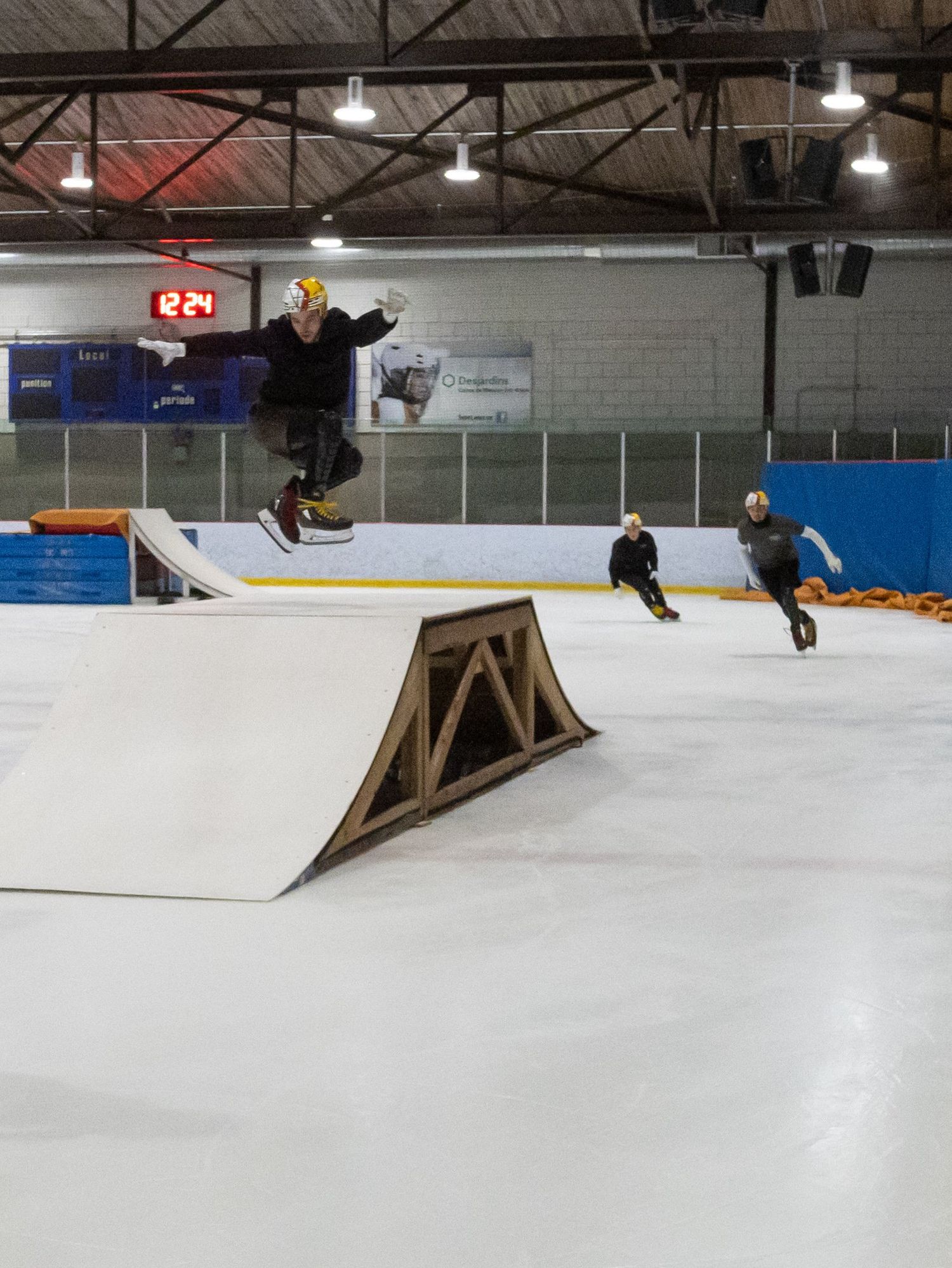 An extreme skater hops over a ramp, while two others follow.