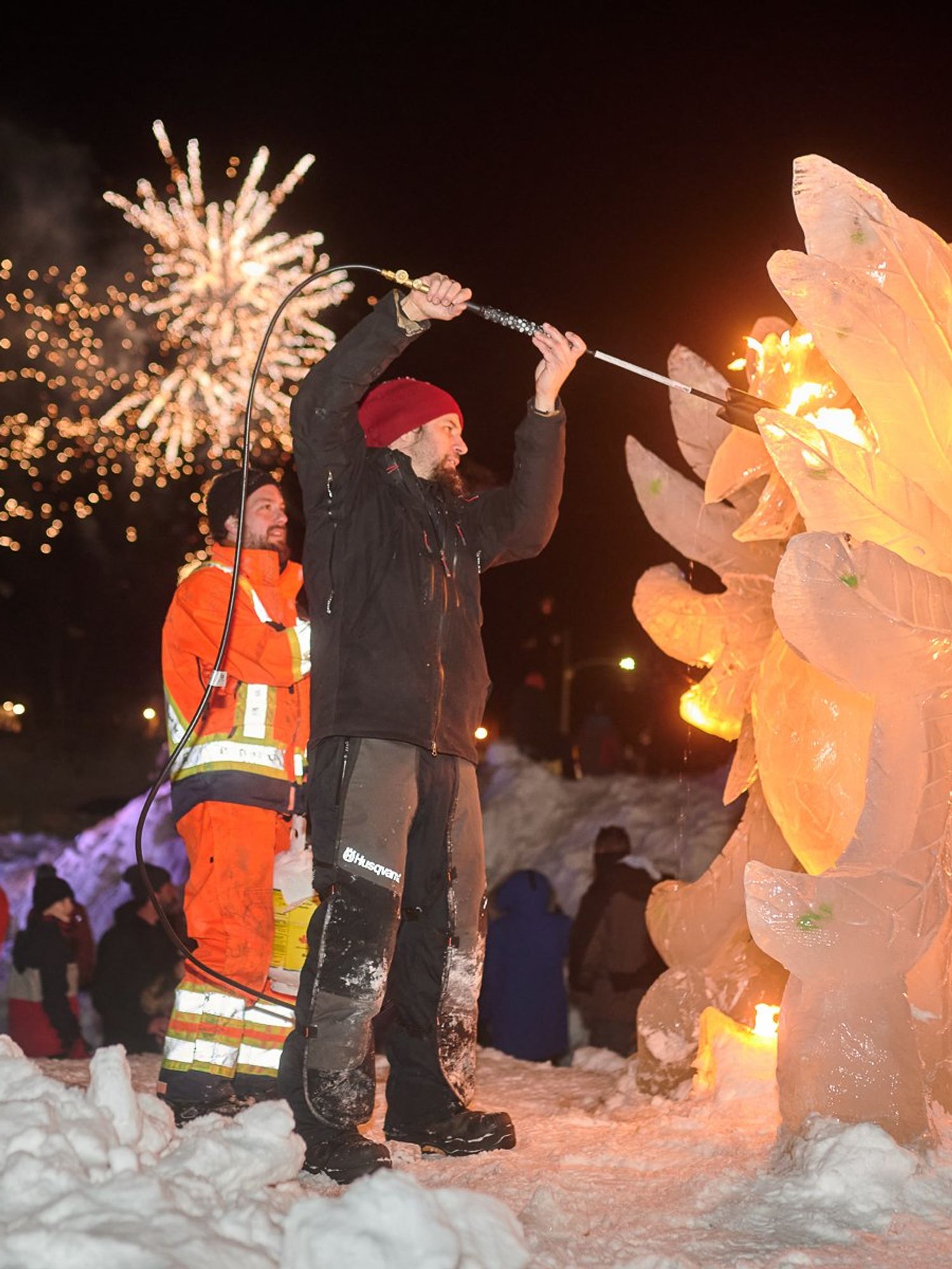 An ice sculptor works on a phoenix during a fireworks show.
