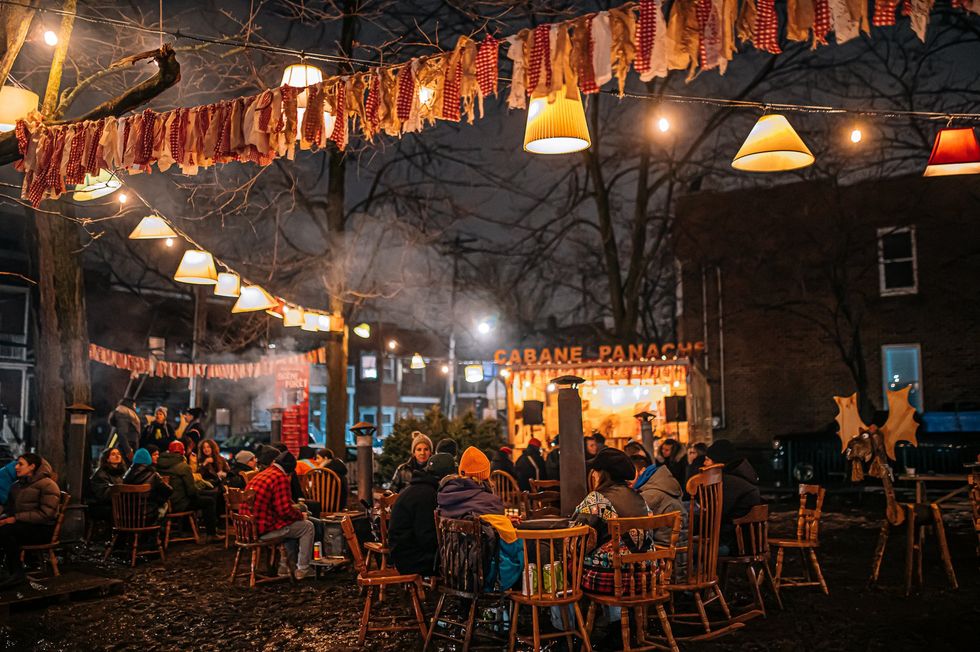An outdoor relaxation area with tables, chairs and heating stations.