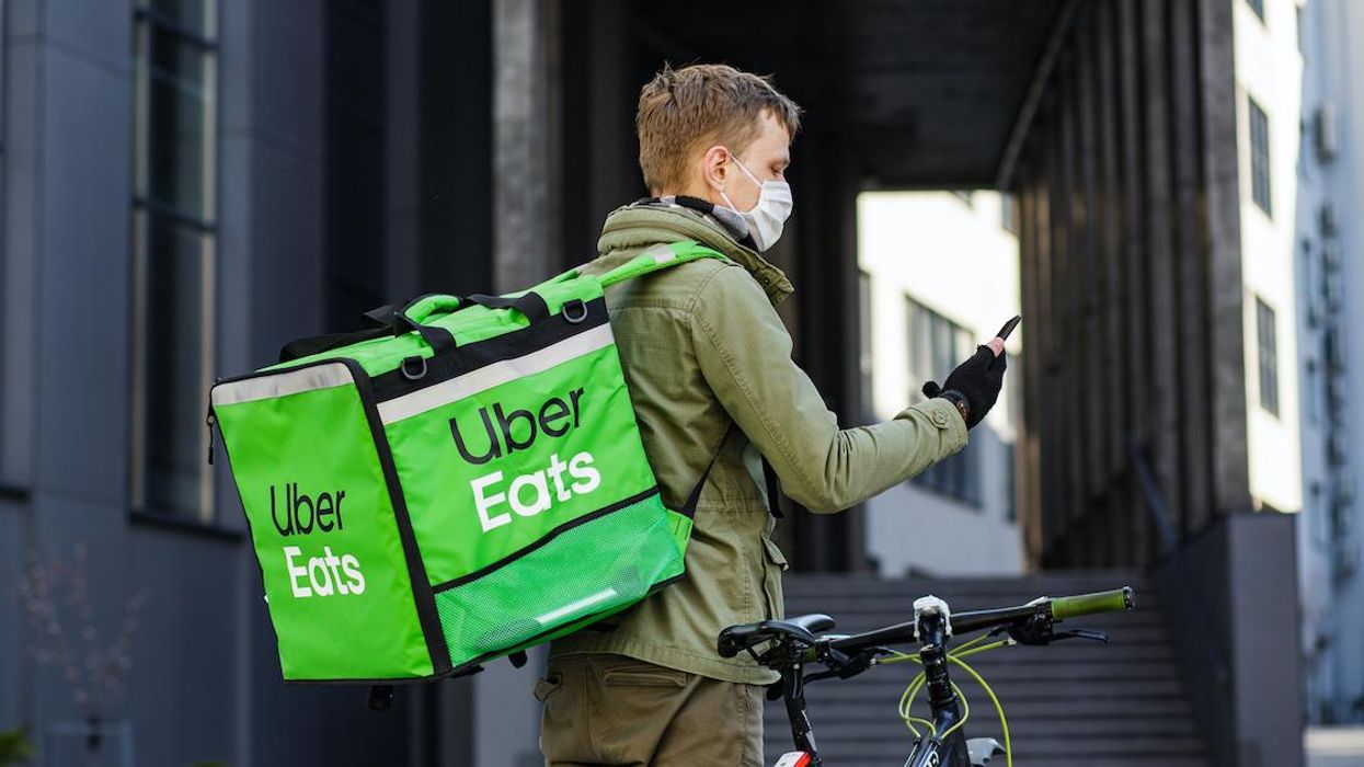 An Uber Eats delivery person checks their phone.