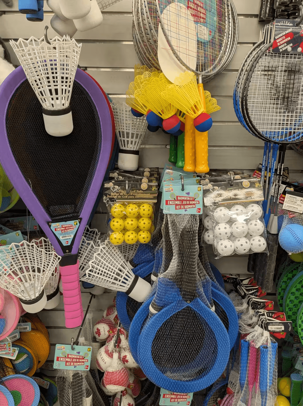 Badminton sets, rackets, and sports equipment on a shelf at Dollarama.