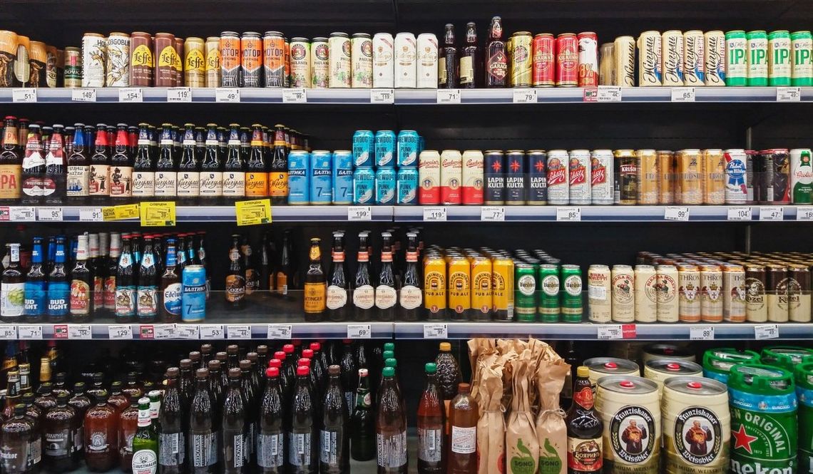 Beer and cider on shelves at a grocery store.