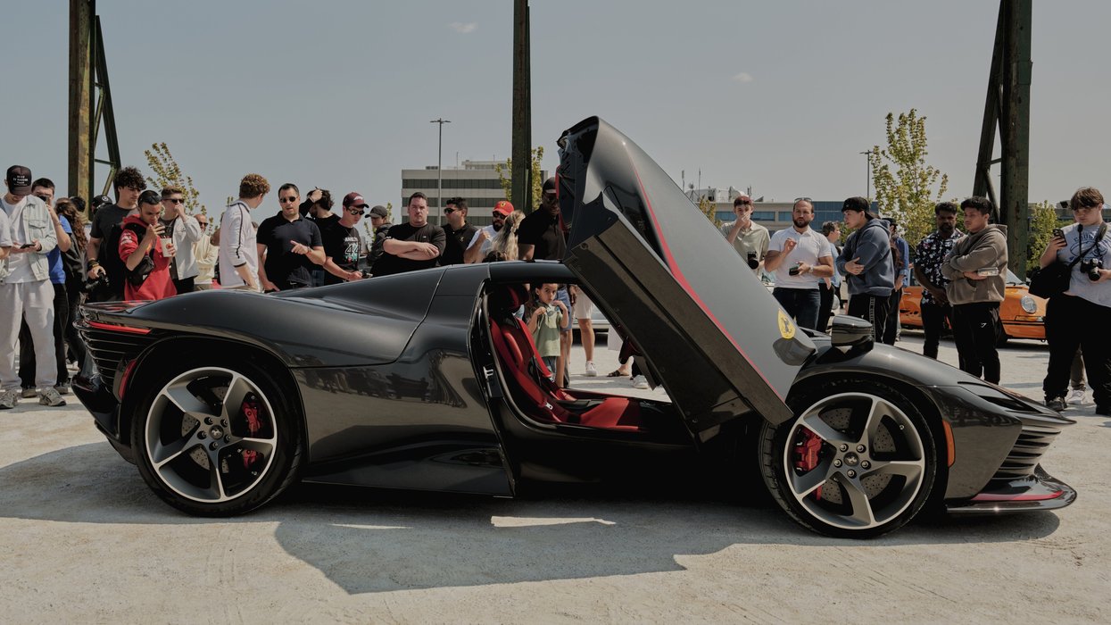 Black luxury supercar with open doors surrounded by crowd at outdoor car event