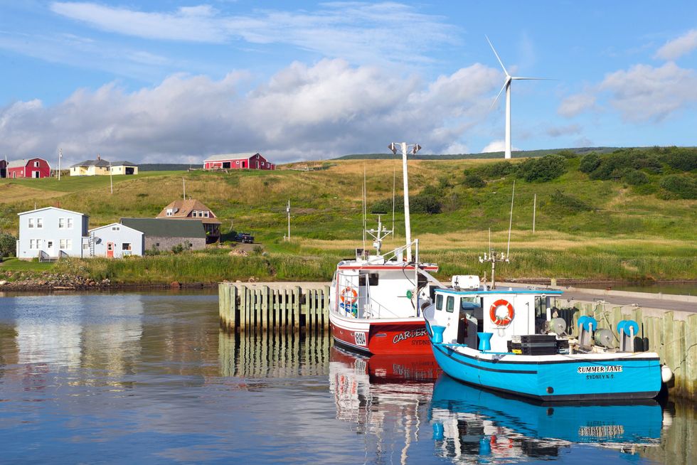 Boats on water and a windmill on hillside in Grand Etang on the famous Cabot Trail in Cape Breton, Nova Scotia.