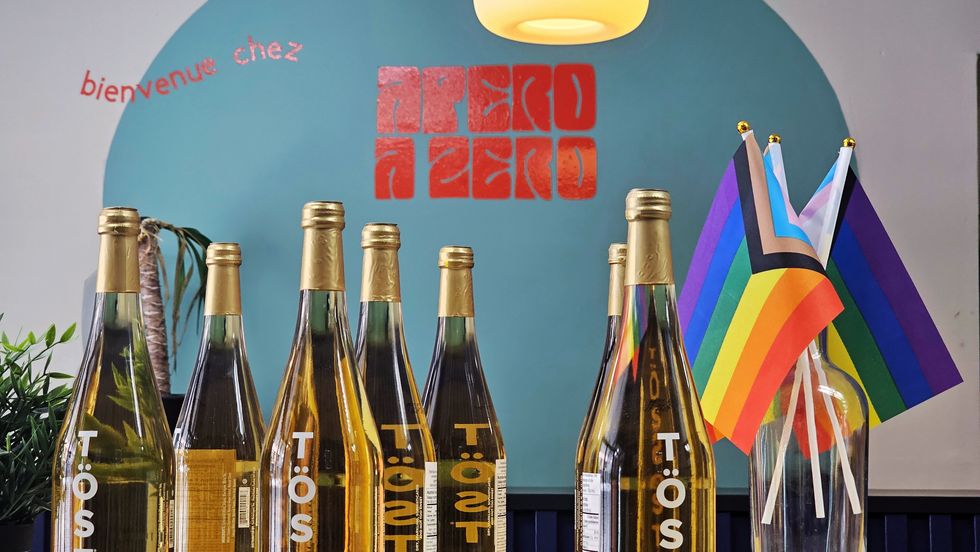 Bottles of TOST, a popular store item, by a vase with inclusive Pride flags.