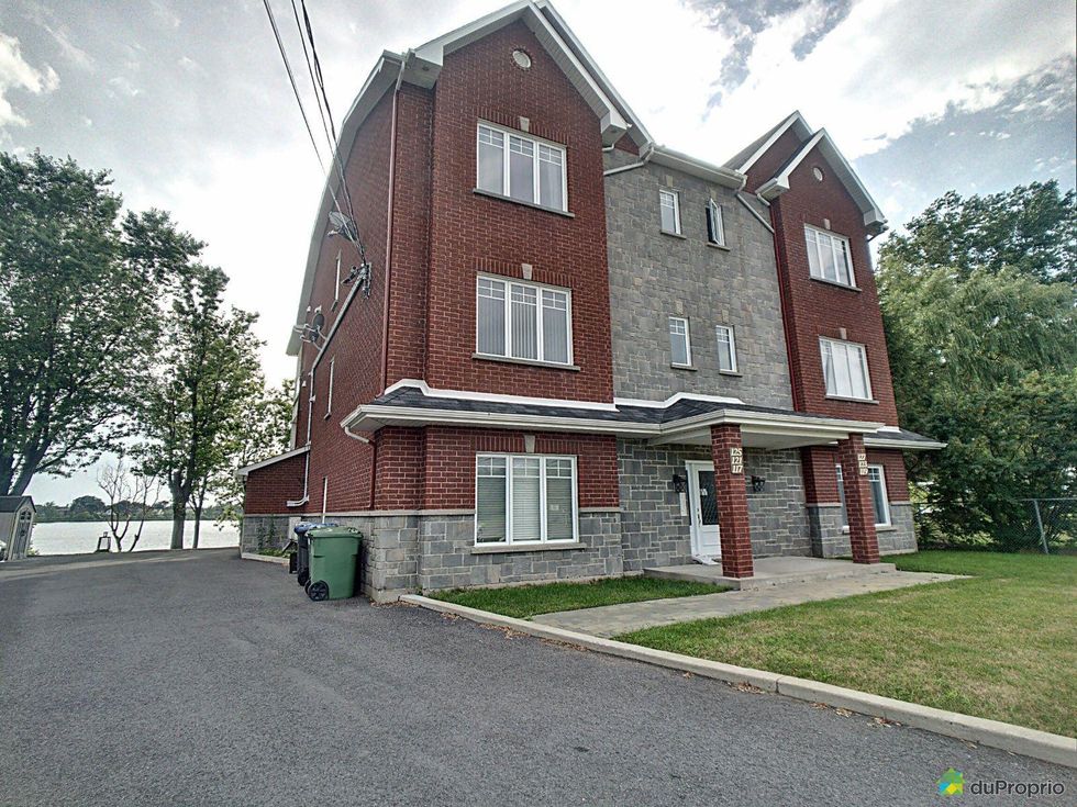 Brick and stone fa\u00e7ade of a three-storey condo for sale in Saint-Jean-sur-Richelieu, Quebec.
