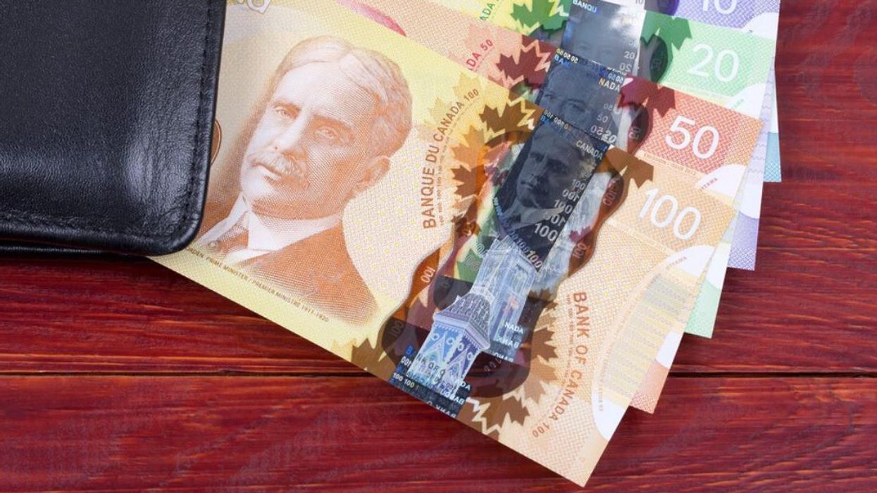 Canadian money tucked in a wallet on a wooden surface.