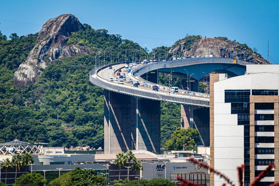 Cars drive by a mountain via Deputy Darcy Castelo de Mendon\u00e7a Bridge in Espirito Santo, which is the second tallest in Brazil.