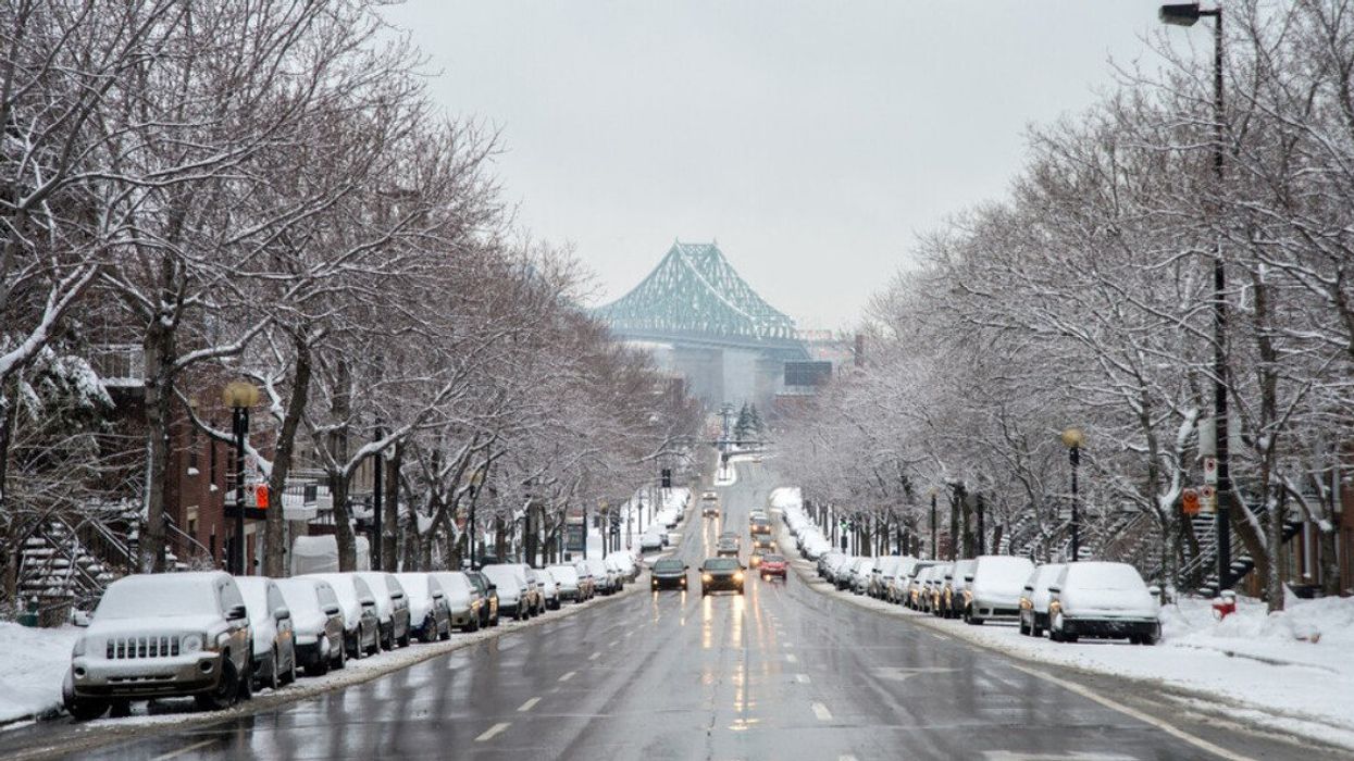 Cars drive on a wet road in Montreal with the Jacques Cartier Bridge after a snow fall.