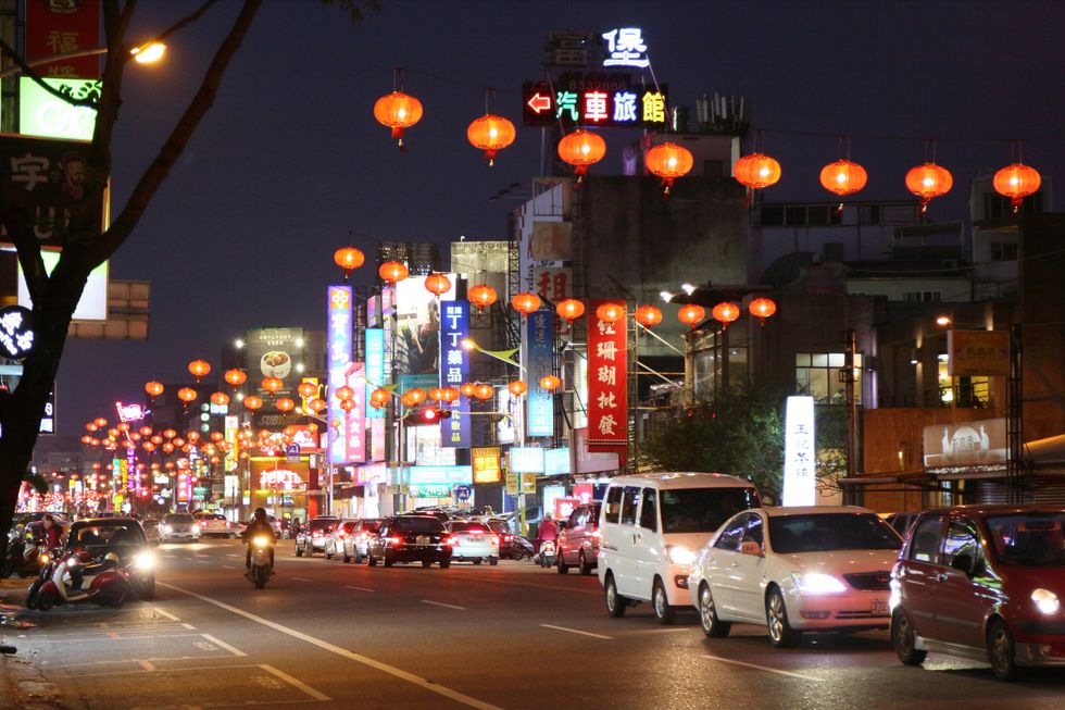 Cars on a road in Hualien City at night, under hanging lanterns.