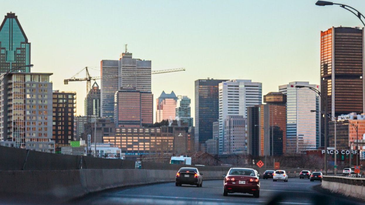 Cars on the road with the Montreal skyline in the background.