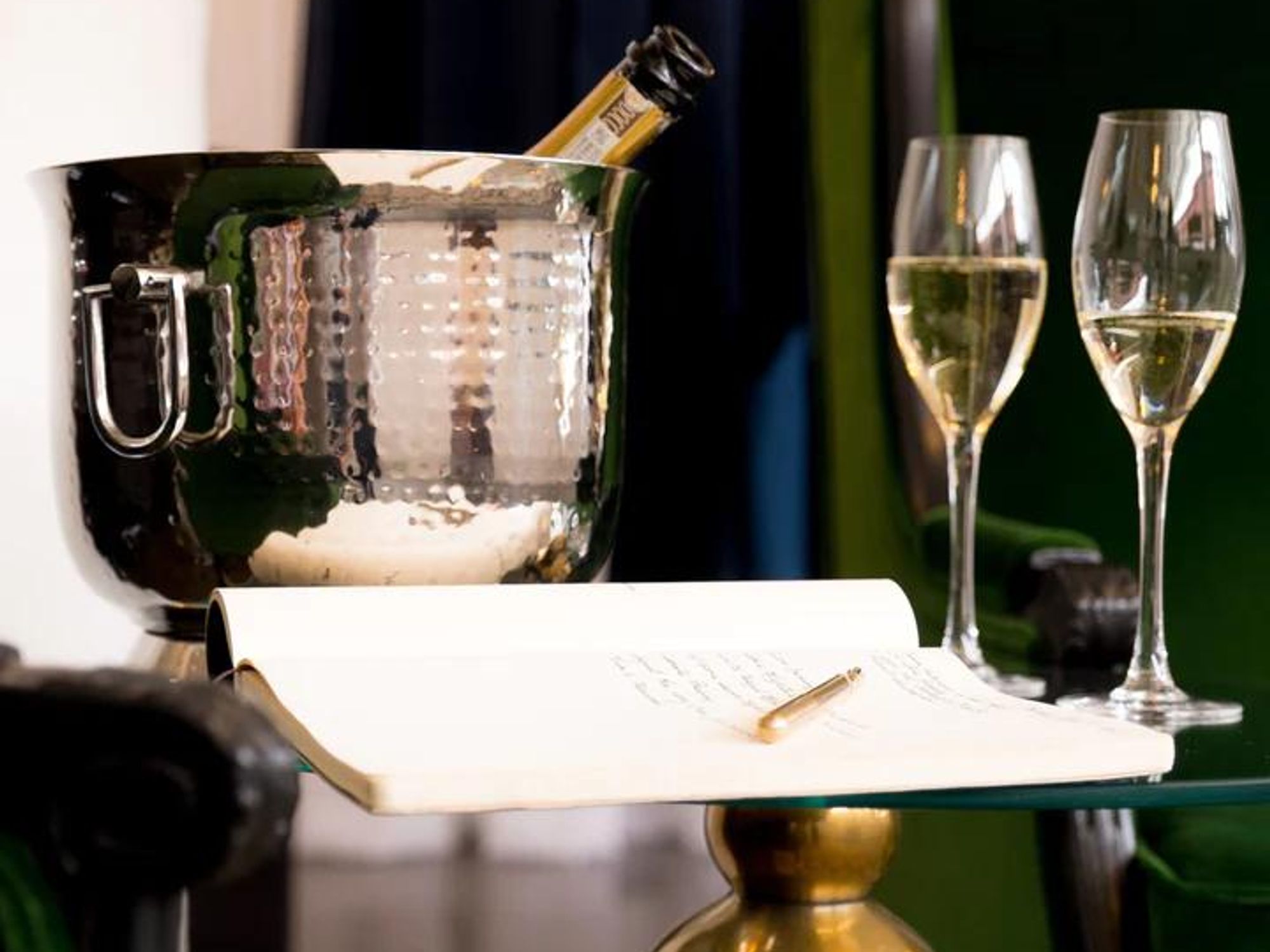 Champagne, glasses and an open notebook on a table.