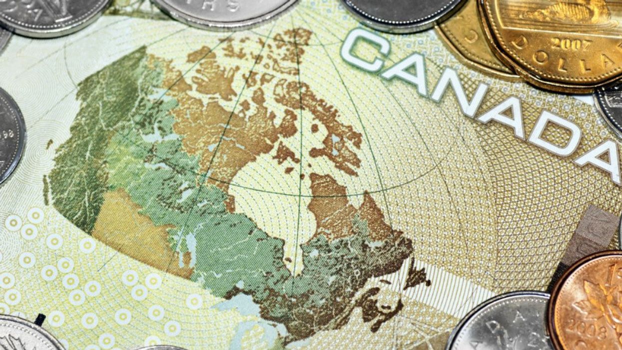 Close up of a one hundred canadian dollar bill showing the map of Canada, surrounded by coins.
