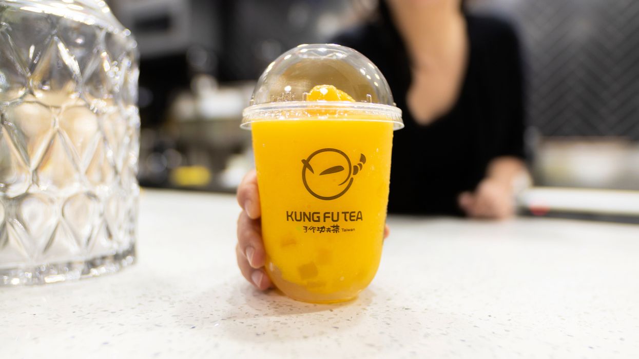 Co-owner Mey Nam holds out a vibrant orange mango slush with aloe vera topping.