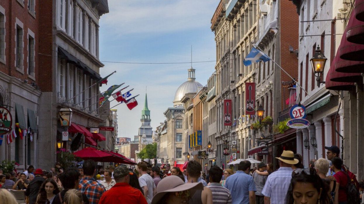 Crowds of people walk the city streets of Old Montreal during a warm, summer afternoon.