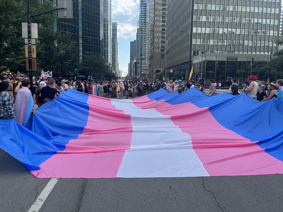 Dozens of volunteers carry an enormous trans flag ahead of the march.