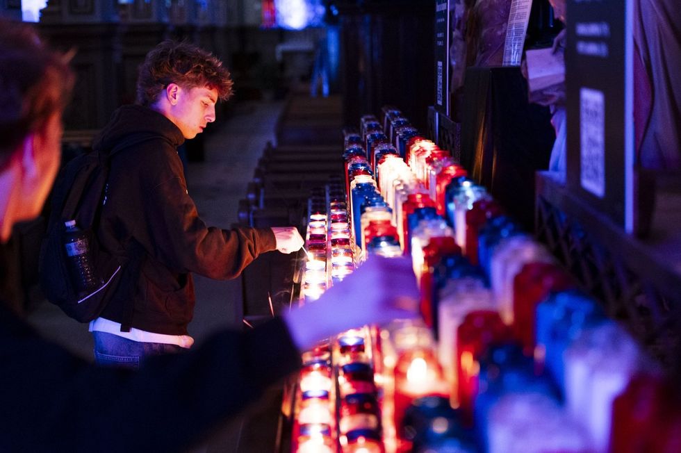 Fans light blue, white and red candles in the Cathedral of Saint-Jean-l'Evangeliste.