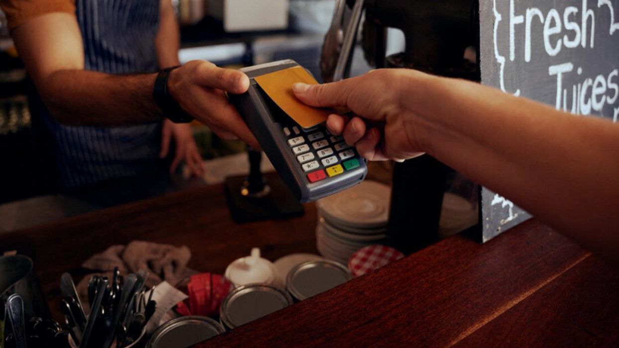 Female hands holding card against payment machine to make payment for purchase in cafe.