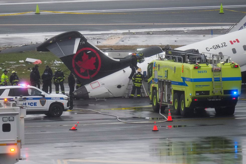 Firefighters and investigators examine the wreckage of an Air Canada plane crash.