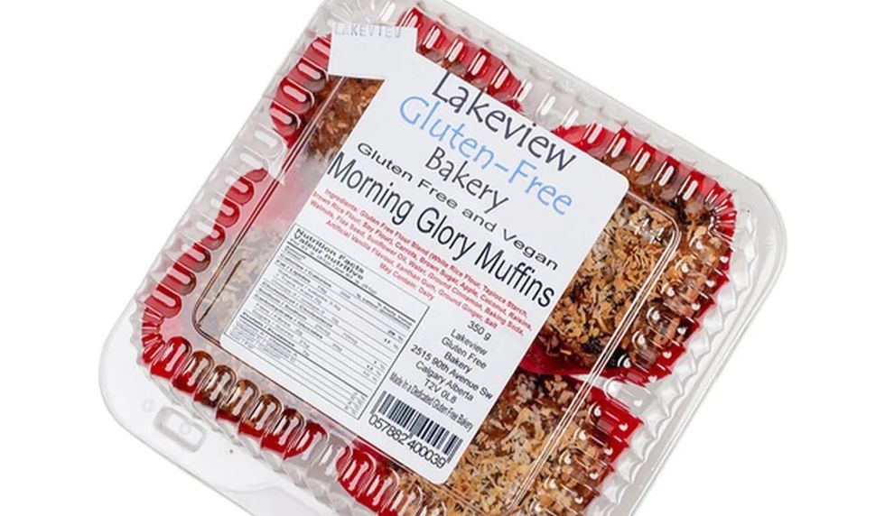 Four gluten-free muffins packaged inside a plastic container enveloped in red lining with the companies label stuck on the front.