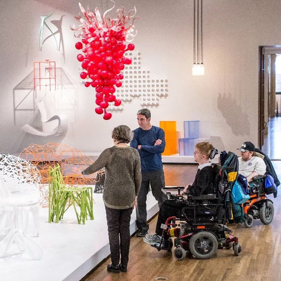 Four people, two in electric wheelchairs, tour sculptures at the museum.