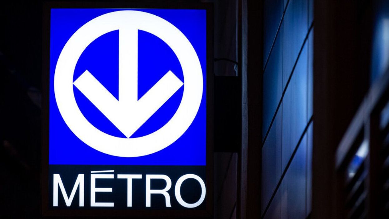 Glowing blue Montreal metro sign at night.