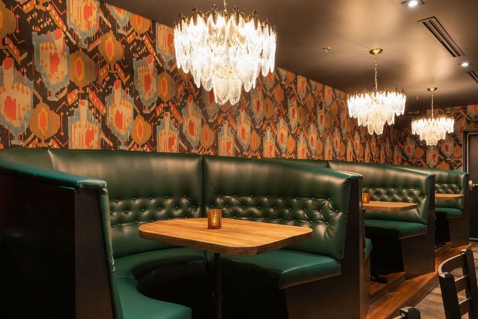 Green booths, patterned wallpaper and ornate lanterns at Jack Saloon.