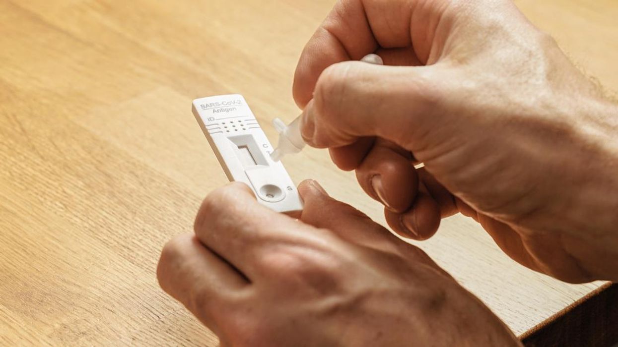 Hands holding a covid-19 rapid antigen test and a tube with liquid.