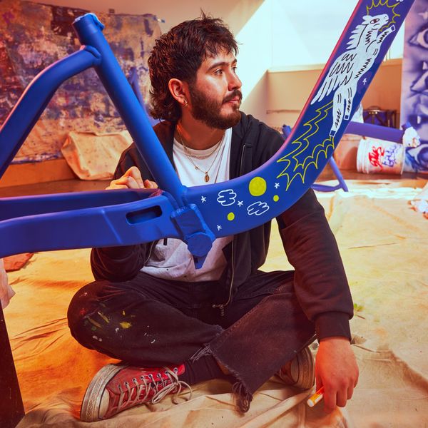 Illustrator Chien Champion sits behind a blue bike frame with a flying horse.