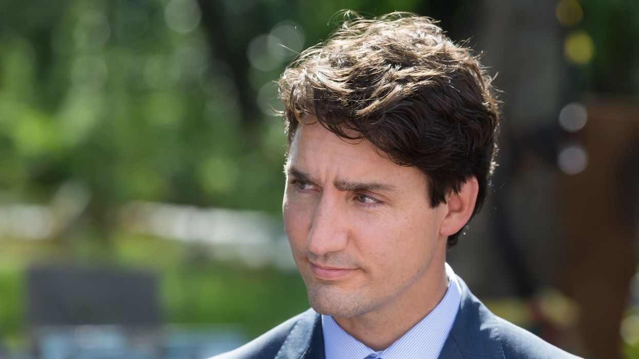 Justin Trudeau in a suit with a blurred green background.