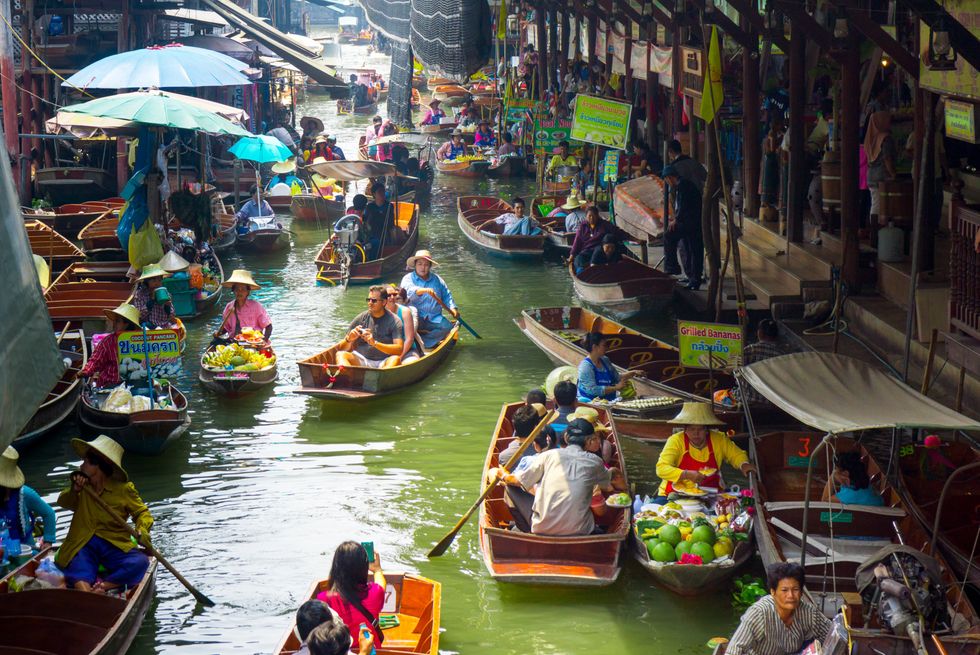Locals sell fruits, food and souvenirs at the famous tourist attraction Damnoen Saduak floating market in Ratchaburi, Thailand.