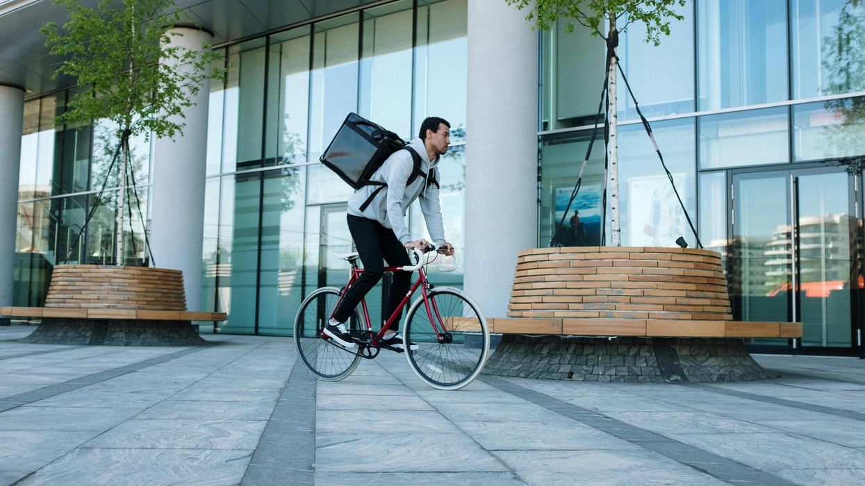 Man riding a bike carrying a thermal bag on his back