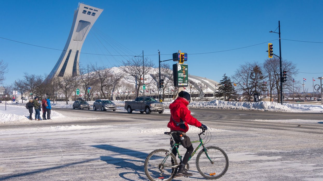 Man riding a bike in winter, in front of Montreal Olympic Stadium.