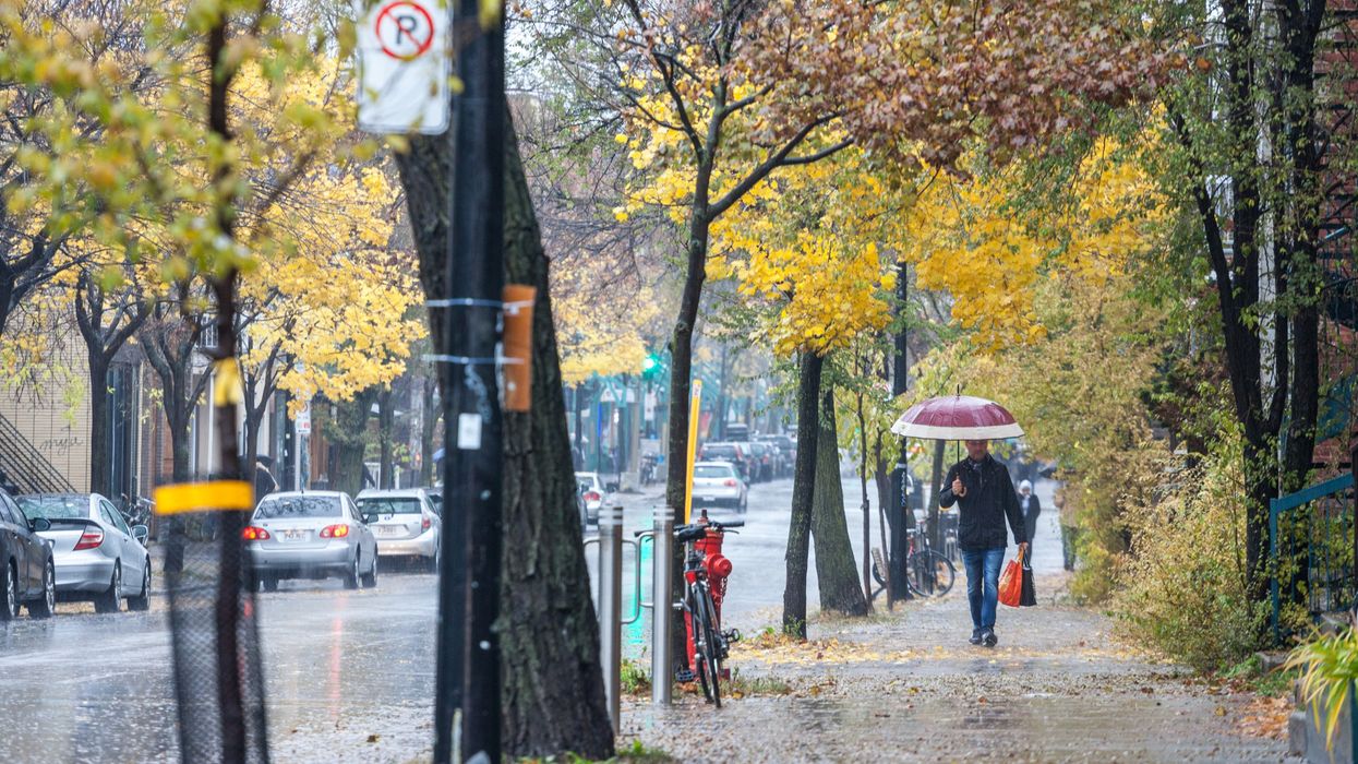 Man walking with an umbrella during a rainy autumn afternoon in a street of le Plateau, a residential district of Montreal, Quebec.
