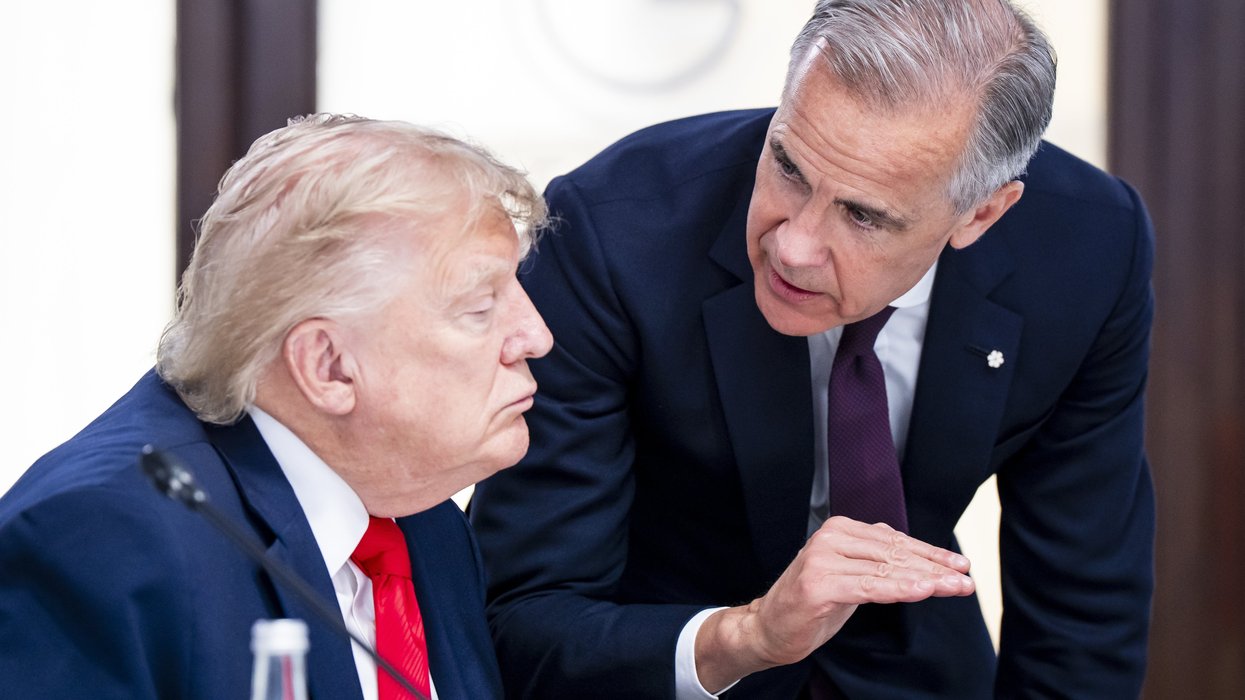 Mark Carney crouches to speak closely to a seated Donald Trump.
