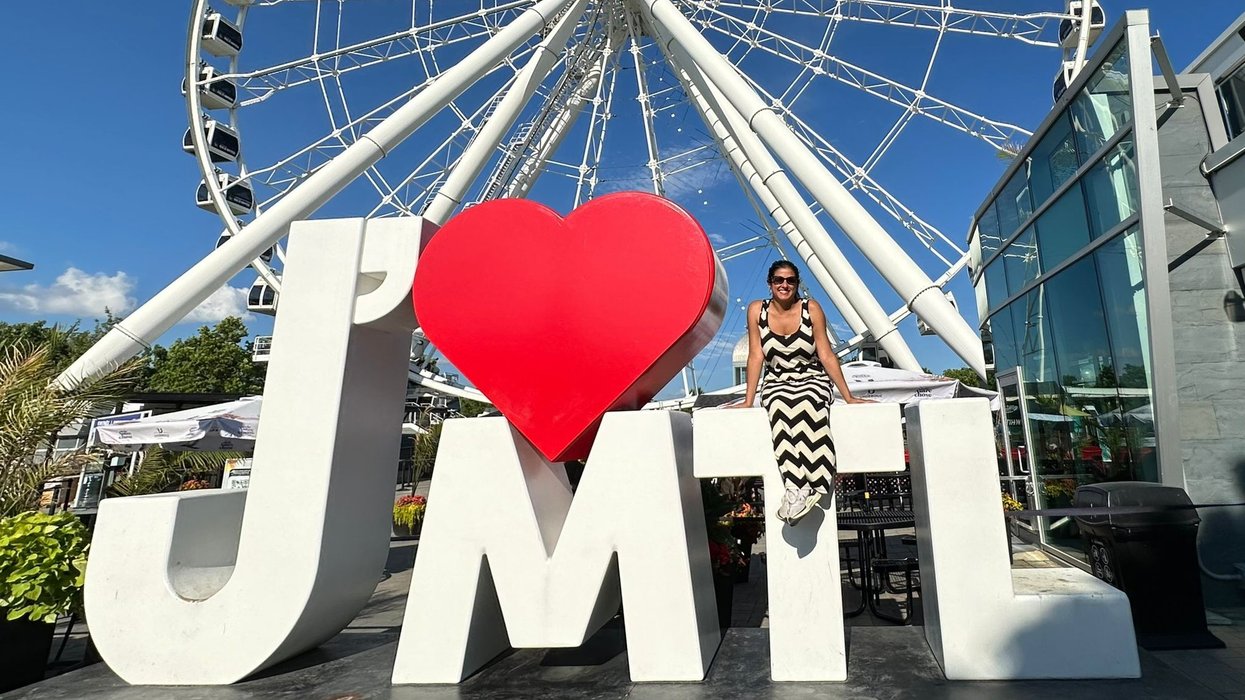 Melanie beside a J'Aime MTL sign in front of the Grande Roue in the Old Port.