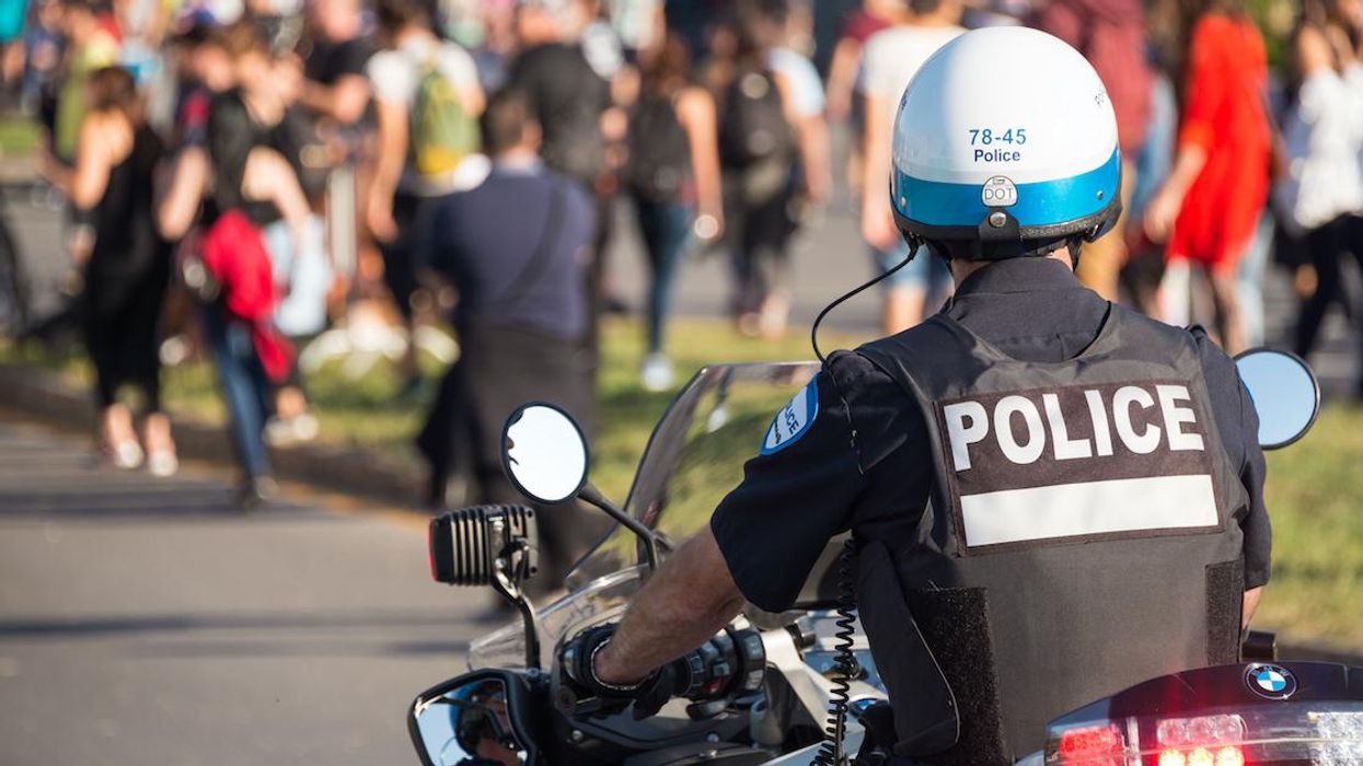 Montreal police officer on a motorcycle with a crowd in the background.