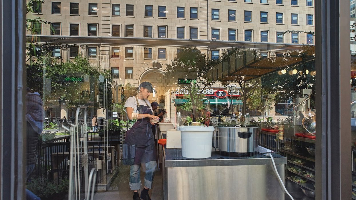 Montreal, Quebec, Canada, September 14, 2018: female cook works at a kuna in a restaurant through window glass in Montreal.