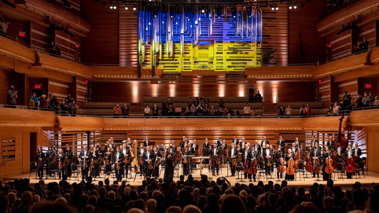 Montreal Symphony Orchestra on stage with a projection of the flag of Ukraine in the background.