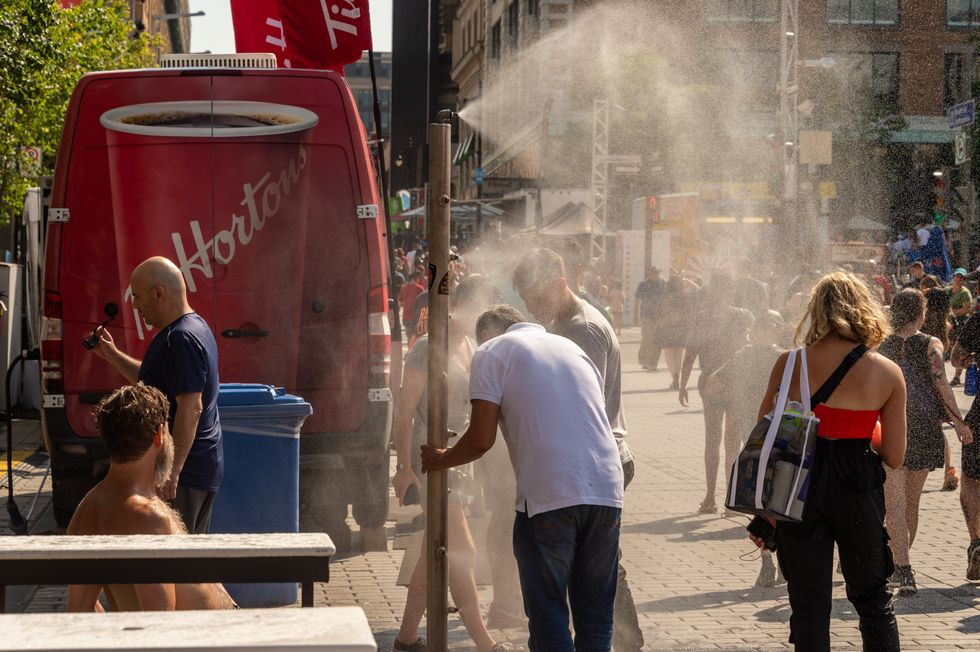 Los habitantes de Montreal caminan bajo un sistema de nebulización para refrescarse durante una ola de calor en el Quartier des festivals de Montreal.