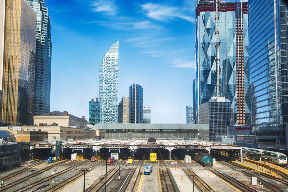 Multiple train tracks leading into Toronto Union station surrounded by skyscrapers.