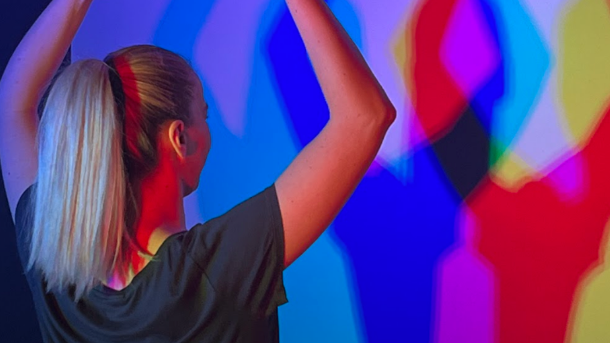 Museum of Illusions staff member Andrea Pinjušić poses in front of coloured lights.