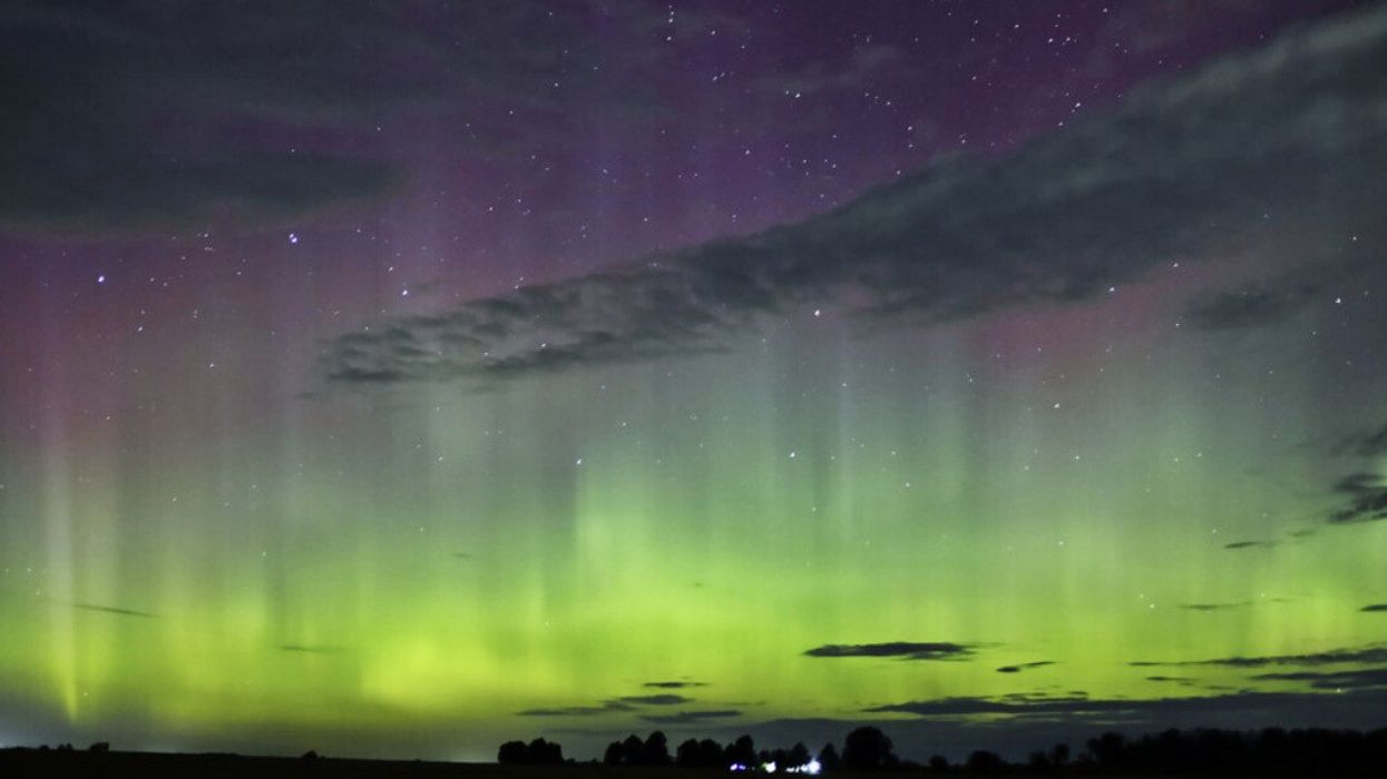 Northern lights appear over a city.