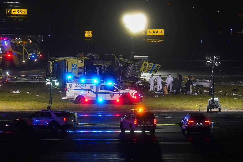 Officials examine the area around a crashed airport fire truck on the runway.